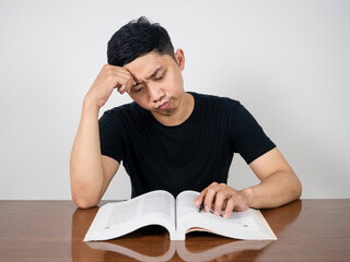 Asian man serious reading text book on the table feels headache