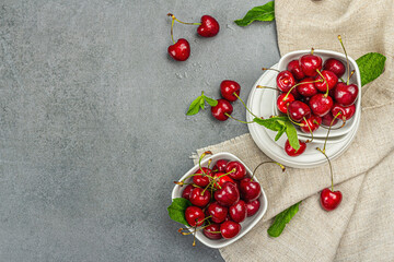 Ripe sweet cherries with fresh mint leaves, traditional summer fruits. Trendy stands, vintage napkin