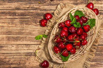 Ripe sweet cherries with fresh mint leaves, traditional summer fruits. Trendy light, vintage napkin