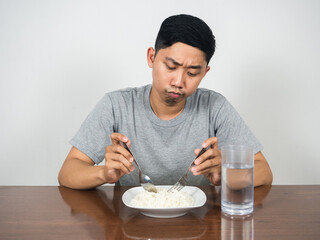 Asian man feels bored food don't want to eatting rice on the table