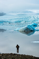 Man jumping in front of a glacier lake