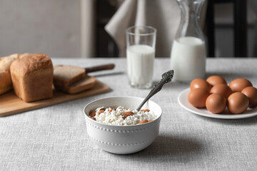 At home, in the kitchen, the table is covered with a linen tablecloth and there are natural and healthy products, milk and cottage cheese, bread and boiled chicken eggs on it