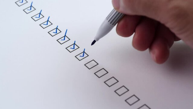 Checklist and To Do List Concept. Close-up businessman tick off or marking with blue mark on checklist, checkbox, to do list box after completing task on white paper. Selective focus 4K resolution