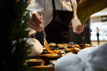 waiter adding sauce on mussels during catering - Powered by Adobe