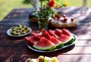 Sliced watermelon and food on a picnic table 
