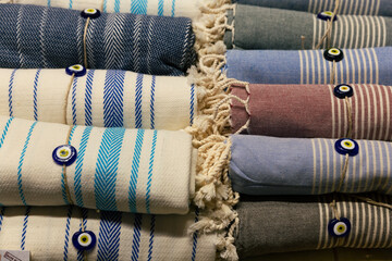 Close shot of traditional Turkish bath towels tied with an evil eye bead - obrazy, fototapety, plakaty