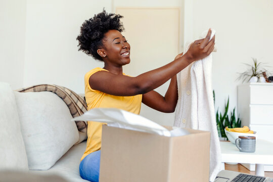 Happy Black Woman Unpacking Box After Online Shopping. Excited Overjoyed Young Woman Shopper Unboxing Parcel Shipped By Mail.