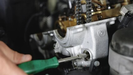 Car Mechanic Assembles Parts Of Car Engine With Screwdriver In The Repair Shop Footage. Car Mechanic Tightens Part Of The Car Engine. Open car engine. Car engine repair. Auto service.