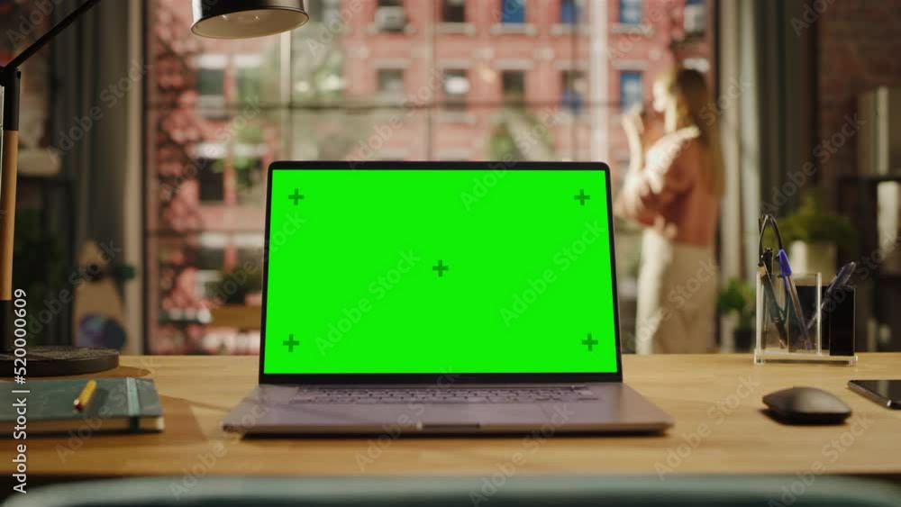 Poster laptop computer display with mock up green screen on a table in living room. chroma key monitor at h