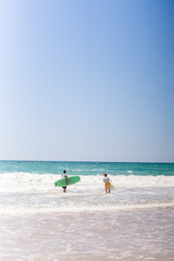 Fototapeta na wymiar surfistas de espalda con tablas de surf entrando al agua