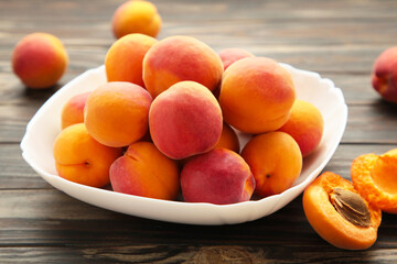Fresh apricots in the bowl on brown wooden background