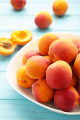 Fresh apricots in the bowl on blue wooden background. Vertical photo