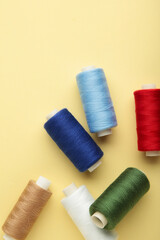 Color sewing threads on beige background. Vertical photo.