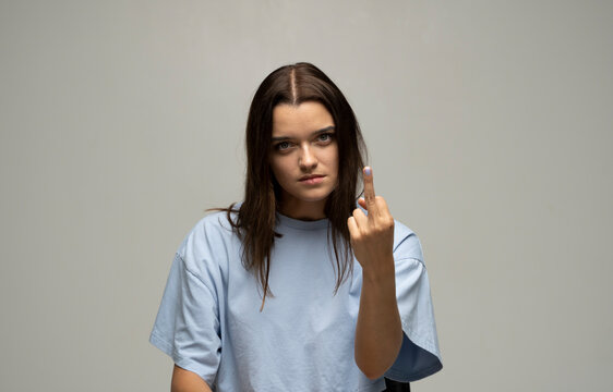 Portrait of crazy angry brunette woman wearing casual style beige t-shirt showing middle finger with one hand, rude gesture, face full of hatred and resentment.