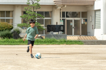 学校でサッカーをしている小学生の男の子