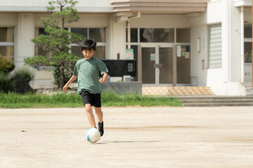 学校でサッカーをしている小学生の男の子