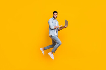 Fototapeta na wymiar Full length photo of cheerful skilled man guy jump up use device laptop isolated on yellow color background