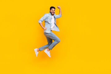 Full body photo of attractive hispanic young guy celebrate job promotion wear stylish jeans clothes isolated on yellow color background