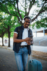 Portrait of african traveler using smart phone and listening to music outside of the train station