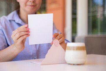 Closeup photography of anonymous woman,holding blank certificate gift certificate gift outside.Cup of coffee near her.