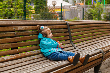 portrait of a little girl in the park on a bench catches soap bubbles