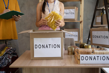 woman volunteer with food in box at distribution or refugee assistance center. charity, donation...