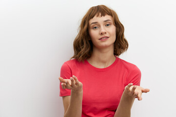  emotional, surprised woman poses standing on a white background in a pink T-shirt, actively...