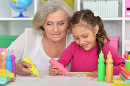 Porait of cute little girl drawing with her grandmother