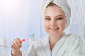 Beautiful girl in a bathrobe brushing her teeth