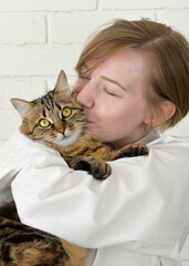 Portrait of young woman holding cute cat with green eyes