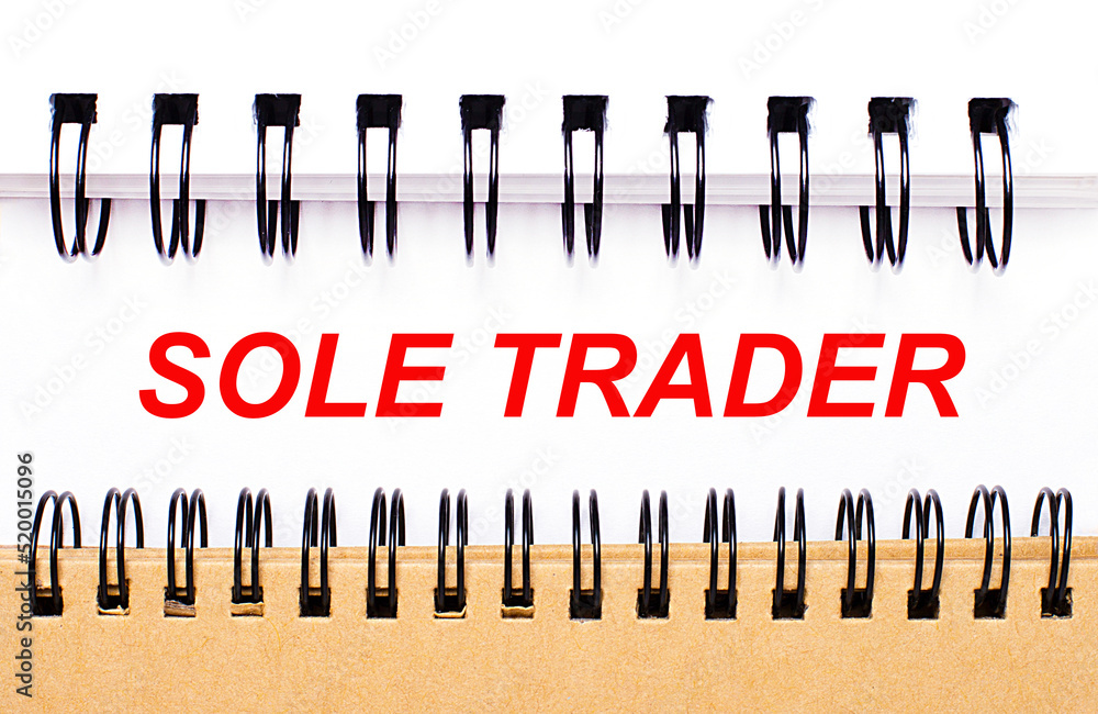 Poster text sole trader on white paper between white and brown spiral notepads.
