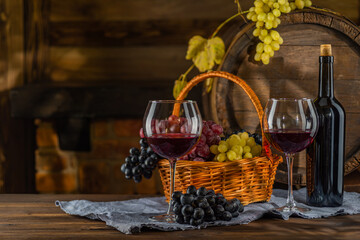Fototapeta na wymiar Glass of wine, bottle of wine, grape in front of the rustic barrels for beverage in a dark wine cellar. Wooden empty surfaces for copy space, mock up, template for design of wine, alcohol products