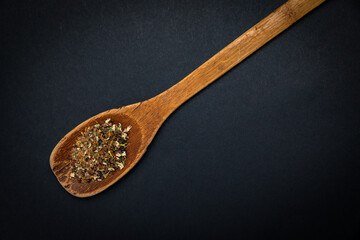 wooden spoon with salt and spices on a dark background
