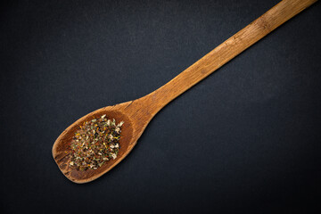 wooden spoon with salt and spices on a dark background
