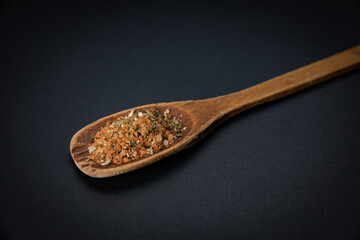 wooden spoon with salt and spices on a dark background
