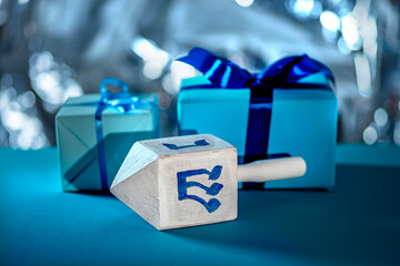 Dreidel, dreidle or dreidl with blue lettering on bright background. Gift box, spinning top, Jewish...