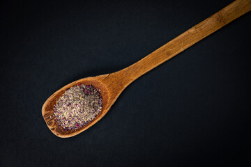 wooden spoon with salt and spices on a dark background

