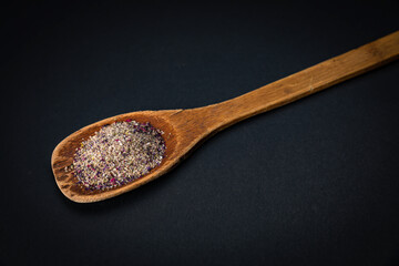 wooden spoon with salt and spices on a dark background
