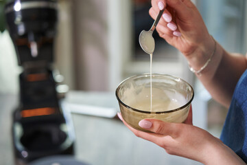 Fototapeta na wymiar liquid white chocolate flows down a teaspoon into a bowl. cake decorating ingredient