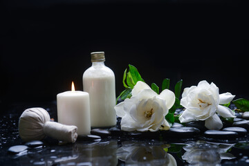 Still life of with 
gardenia with green leaves, and spa ball ,candle  zen black stones on wet background
