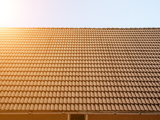 Red tiled roof. Side view. The roof of the house with a brand new red tiled masonry against the sky in the rays of the sun. Soft focus.