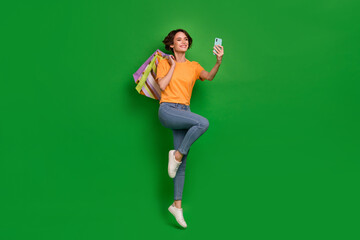 Full body portrait of pretty cheerful girl jump hold telephone make selfie isolated on green color background