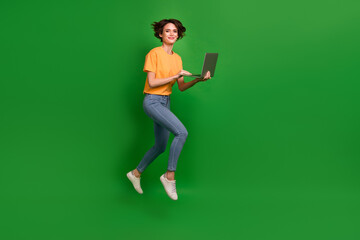 Full body profile photo of attractive lady jump hands hold use wireless netbook isolated on green color background