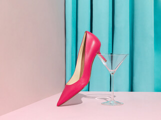 Minimal layout with pink women's shoe in a martini glass. Creative scene sustainable fashion with a...