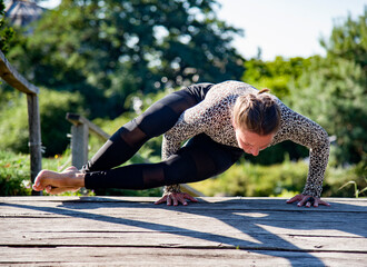 woman  practicing yoga in the park on old bridge in summer sunny morning