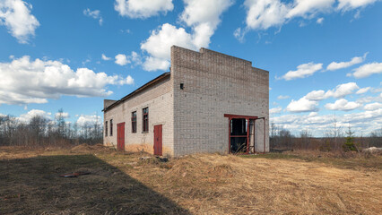 A small abandoned brick industrial building outside during the day.