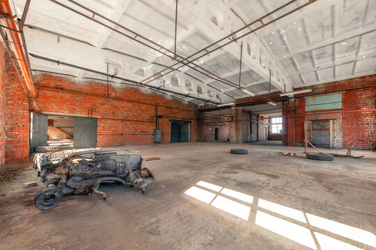 Interior of an abandoned industrial building with a broken car