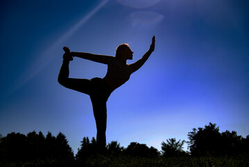 silhouette of a young woman doing yoga in the in the forest at sunrise