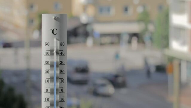 Thermometer with traffic in the background shows increasing temperature.