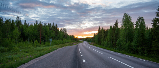 Winding road in forest at sunset